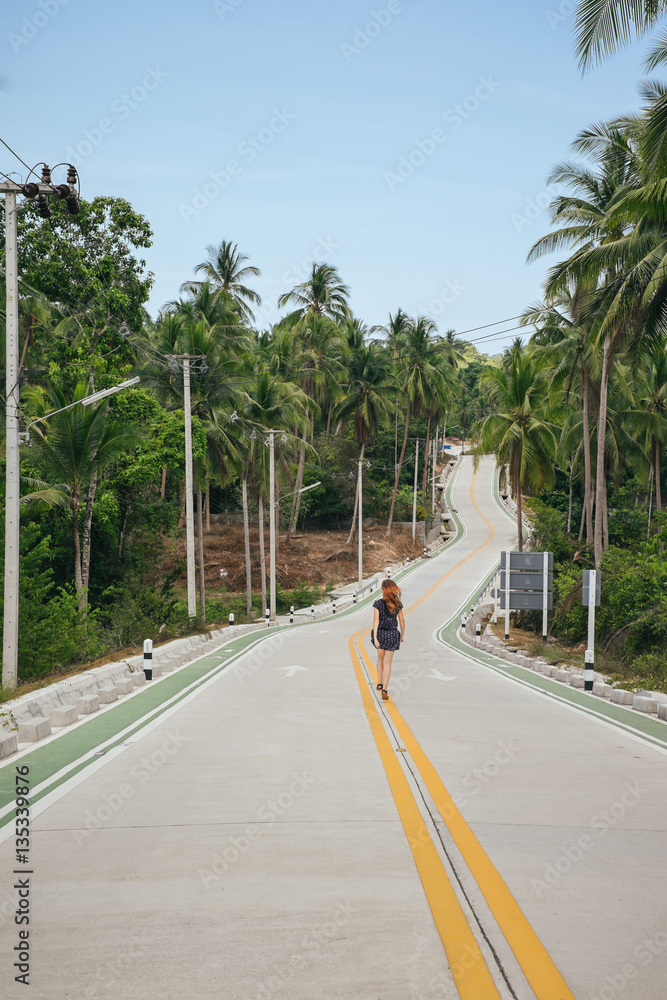 Woman walking on tropical island on empty forest road