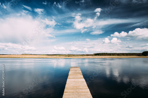 Old Wooden Boards Pier On Calm Water Of Lake Or River At Evening