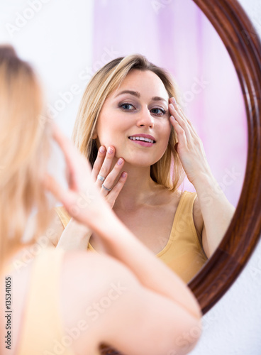 Young woman looking in the mirror.