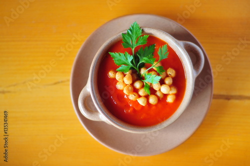 Tomato soup in bowl on wooden table, view from top