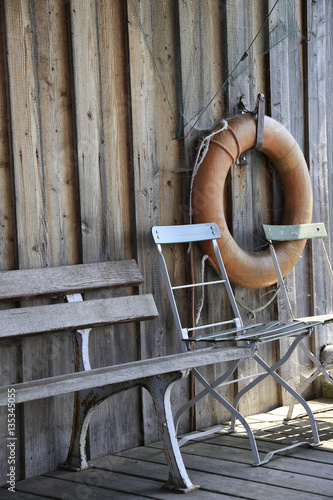 Rettungsring, Bank und Stühle auf einem alten Bootshaus und Fähranleger auf der Roseninsel am Starnberger See, Bayern