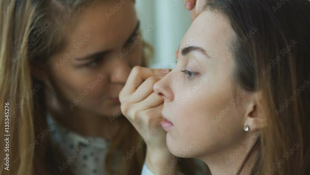 Young make-up artist makes a girl beautiful makeup for eyes closeup before an important event Young make-up artist makes a girl beautiful makeup for eyes closeup before an important event