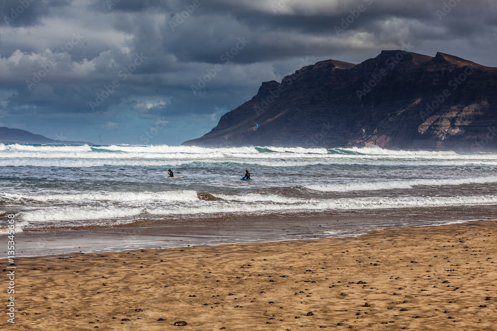 Surfers and kiters in the sea at Famara beach 