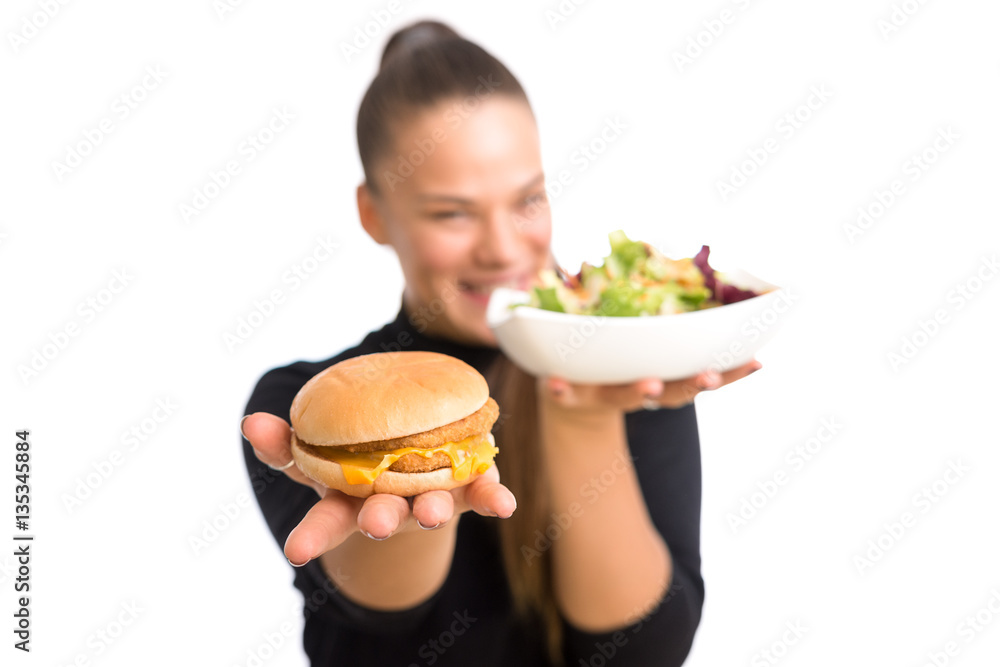 Young woman holding a cheeseburger and plate with salad, isolated against white background. Young woman holding a cheeseburger and plate with salad, isolated against white background.
