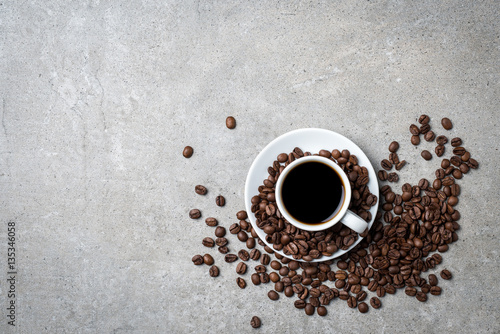 Filiżanka kawy z kawowymi fasolami na popielatym kamiennym tle. Widok z góry