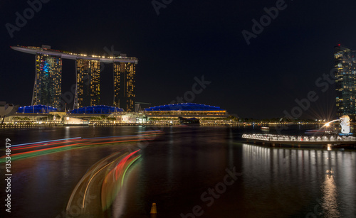 night time cityscape of Singapore with light reflections in the water - built on reclaimed land
