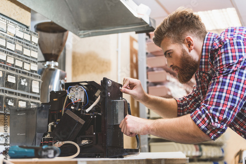 Slika na platnu Serious man repairing broken coffee machine
