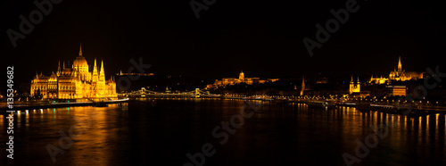Panoramic night view on Hungarian Parliament Building located at the bank of the Dunabe river with famous Chain Bridge connecting Buda and Pest in Budapest  Hungary