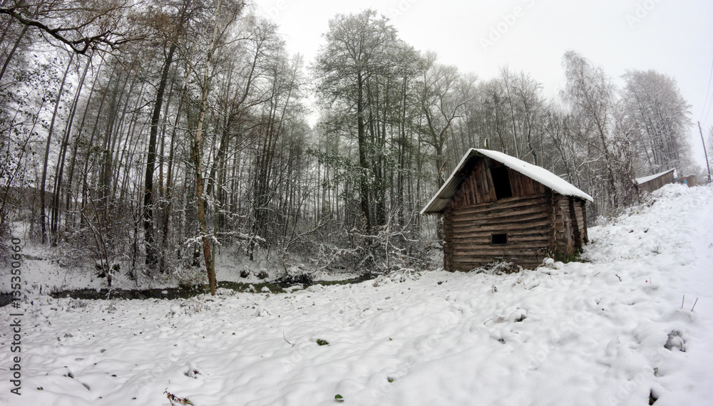 Old wooden bath on the banks of the creek in the woods among the trees. Winter snow. Old wooden bath on the banks of the creek in the woods among the trees. Winter snow.
