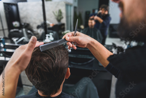 Hairdresser doing hairstyle for young man
