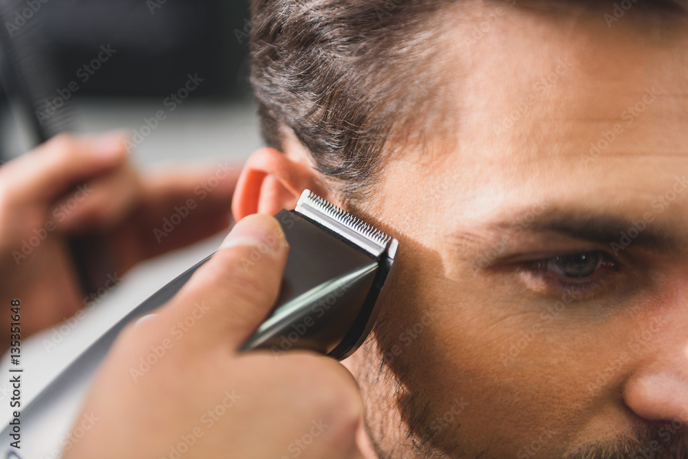 Fotografie Calm man getting haircut by machine