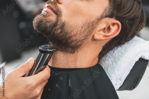 Barber leveling human stubble by shearer