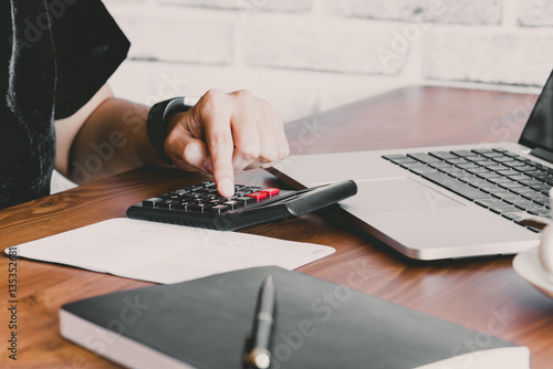 Business women work with calculator and laptop,pen and notebook