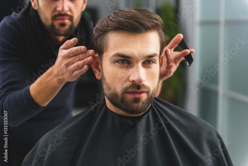 Handsome guy getting haircut at salon