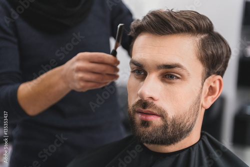 Handsome guy getting haircut by barber