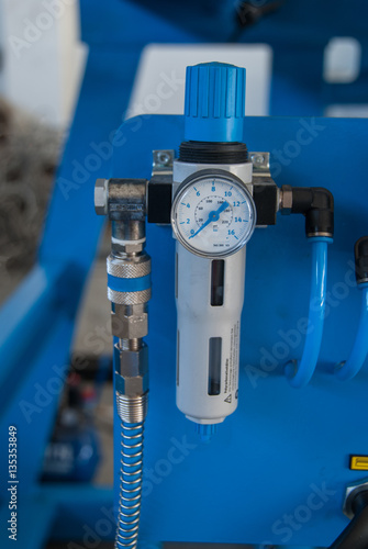 Pressure gauge on pneumatic machine component with blue background