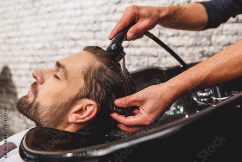 Professional barber undergoing hairwash at salon