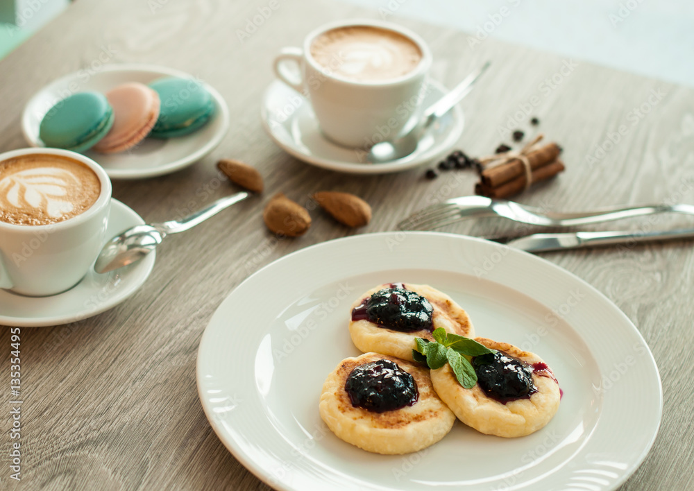 Cheesecakes for breakfast with jam and cappuccino coffee. banner for cafes and restaurants Cheesecakes for breakfast with jam and cappuccino coffee. banner for cafes and restaurants
