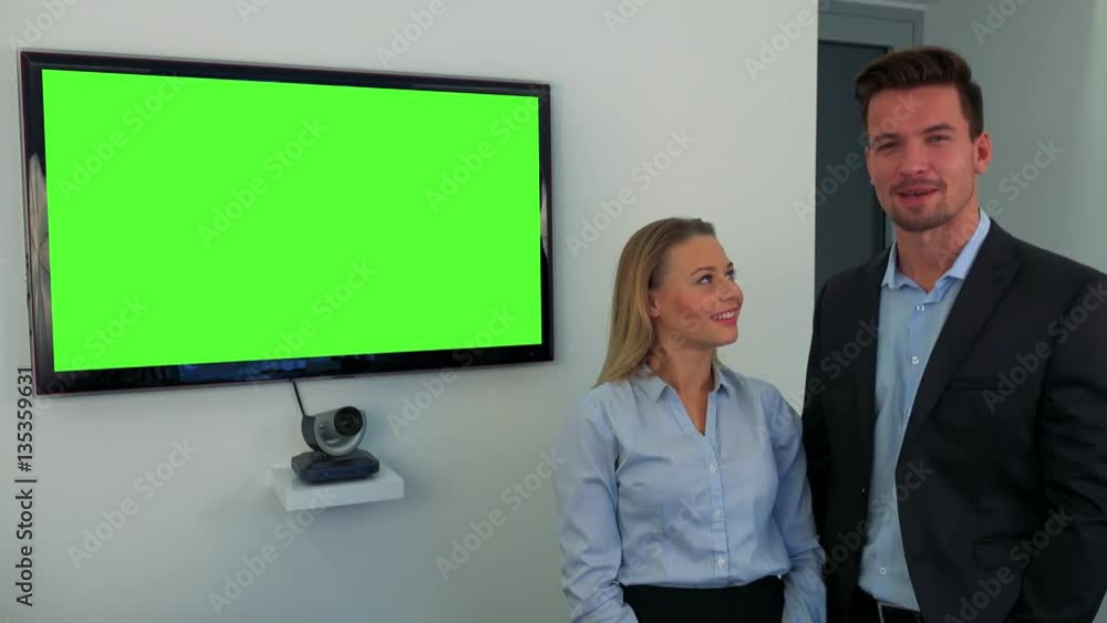 A man and a woman (both young and attractive) stand beside a green television screen and talk to the camera A man and a woman (both young and attractive) stand beside a green television screen and talk to the camera