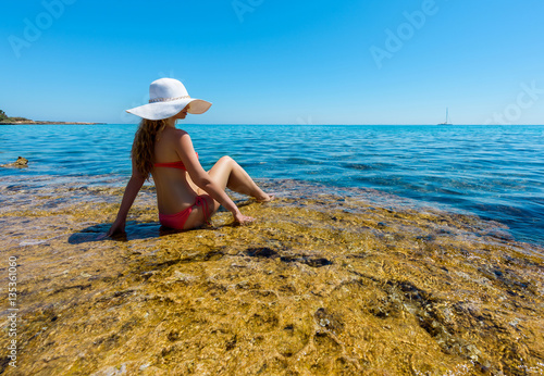 Young woman on the coast of the island. Portrait of a girl in white hat looki...