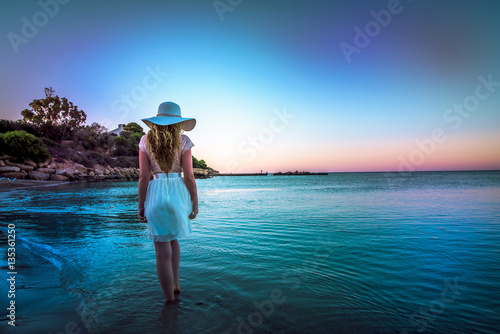 Woman walking down the beach at sunset. Beautiful Sunset sea view in Cyprus i...