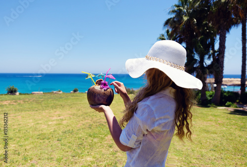 Young Woman drinking Coconut Cocktail at the beach. Summer Portrait of a Pret...