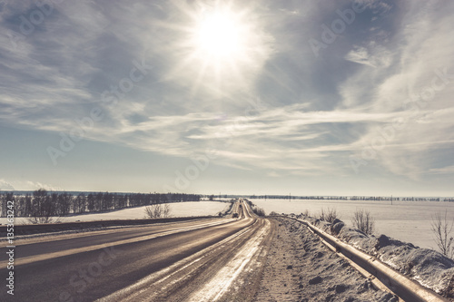Asphalt road in snowy winter on beautiful frosty sunny day. Retro toned picture © DedMityay