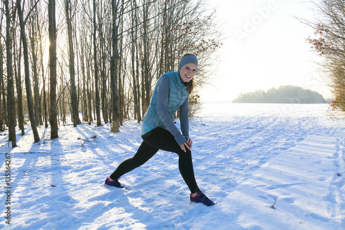 Blond Woman in riemer Park in winter is stretching after jogging