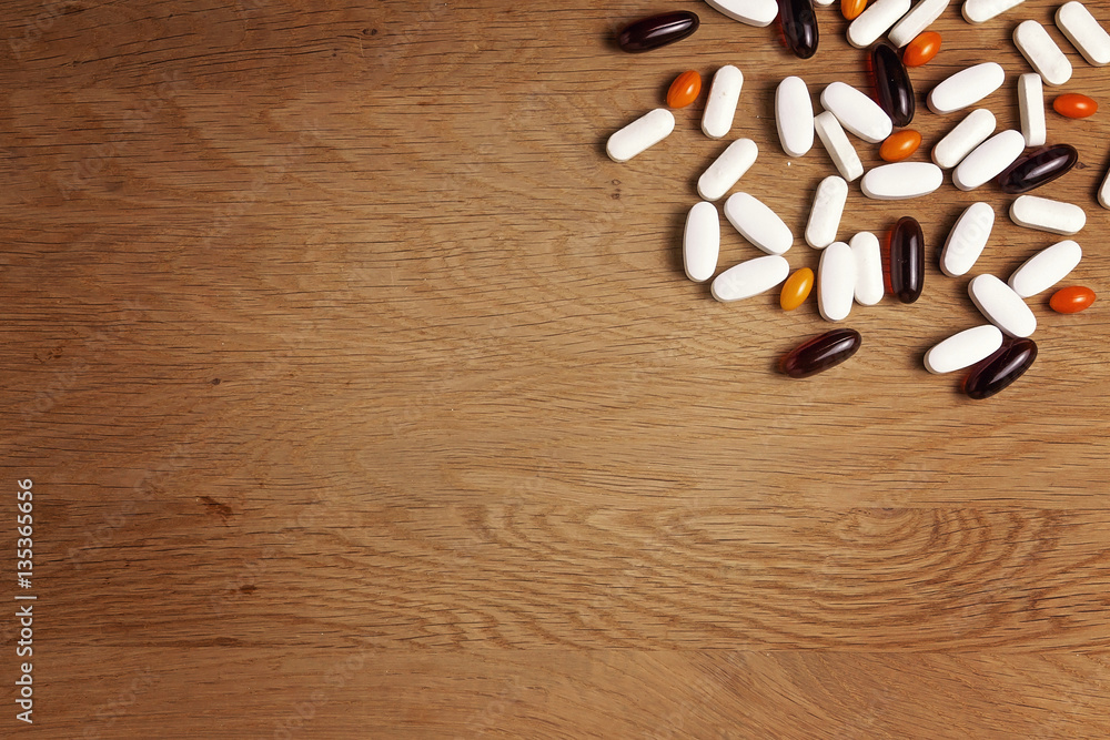 Pills background. Vitamins, dietary supplements, drugs, tablets on wooden table. Pharmacy, medicine and health concept. Pills background. Vitamins, dietary supplements, drugs, tablets on wooden table. Pharmacy, medicine and health concept.