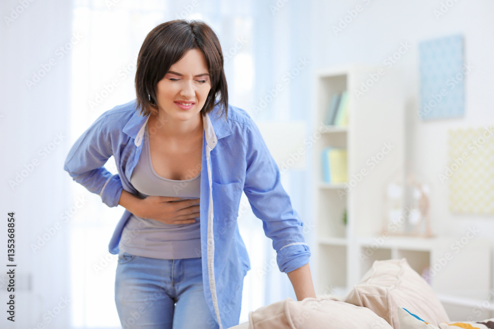 Beautiful young woman suffering from stomach ache at home Beautiful young woman suffering from stomach ache at home