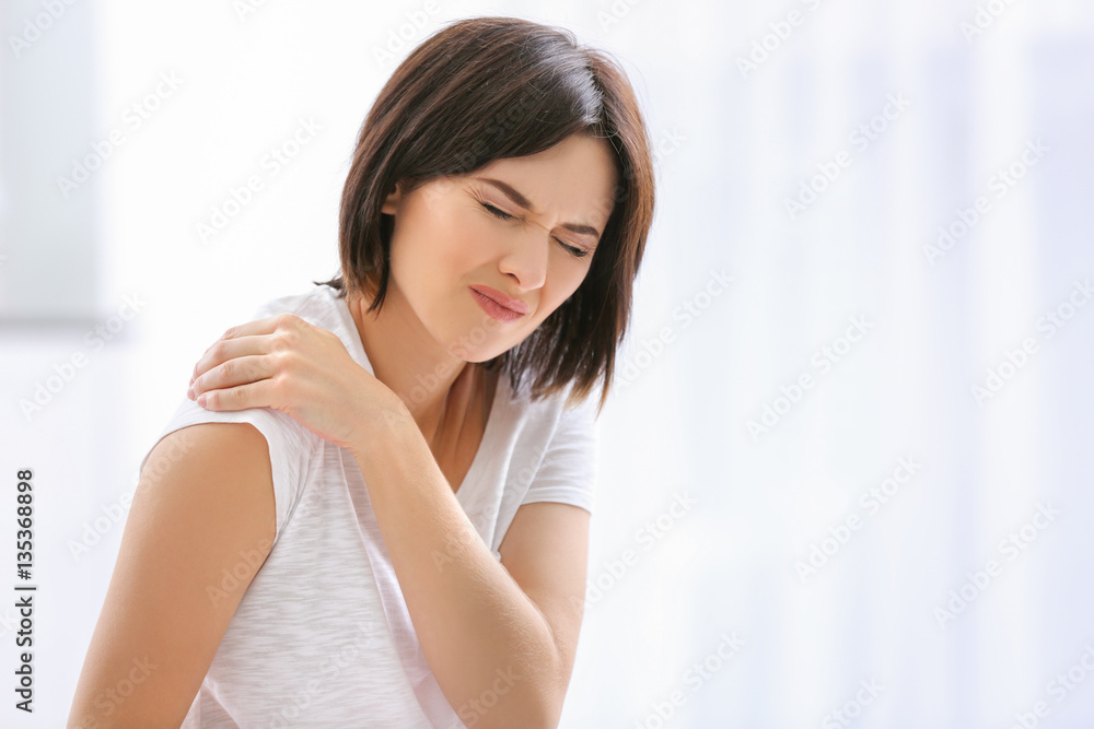 Beautiful young woman suffering from pain in shoulder at home Beautiful young woman suffering from pain in shoulder at home