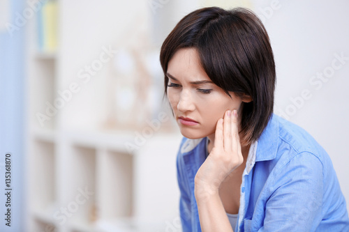Beautiful young woman suffering from toothache at home