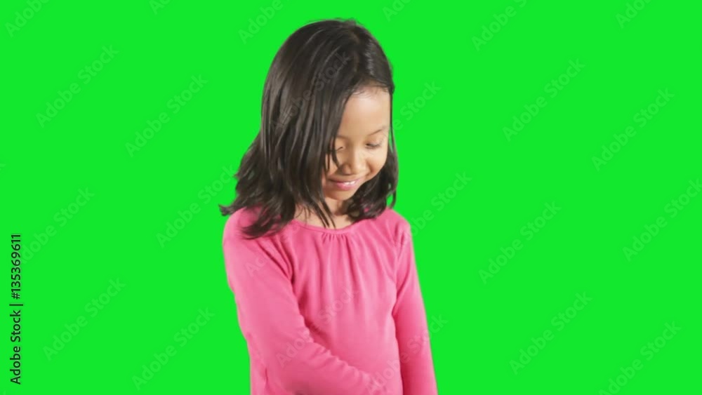 Cute little girl standing in the studio and looks shy, shot with green background Cute little girl standing in the studio and looks shy, shot with green background