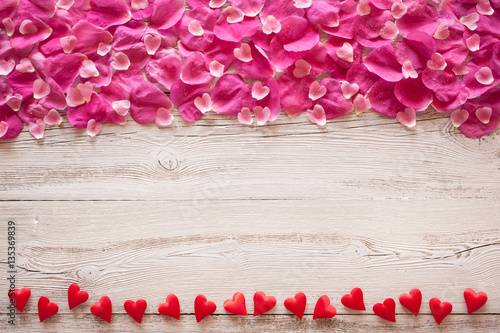 Wooden background with rose petals and hearts