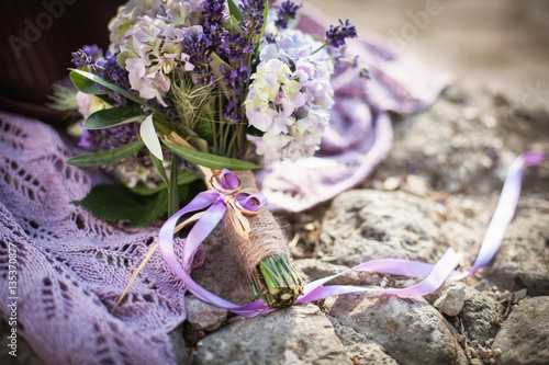 Golden wedding rings are on bouquet from lavender, hydrangea, pi