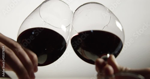 Isolated low angle slow motion shot of two red wine glasses tapping to cheers.