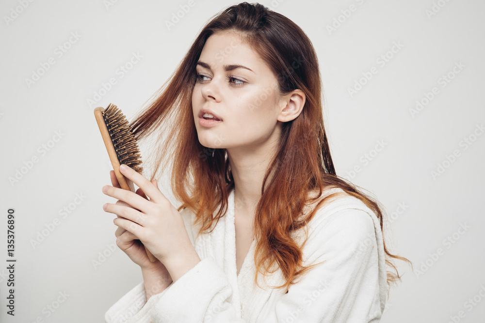 Fototapeta premium woman combs her hair with a wooden massage