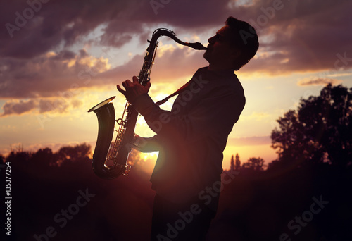 Bild auf Leinwand Saxophonist playing sax against sunset