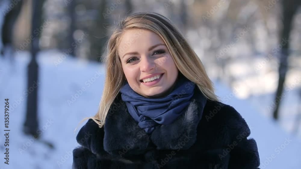 Portrait of attractive beautiful blonde girl smiling and posing to camera in winter park Portrait of attractive beautiful blonde girl smiling and posing to camera in winter park