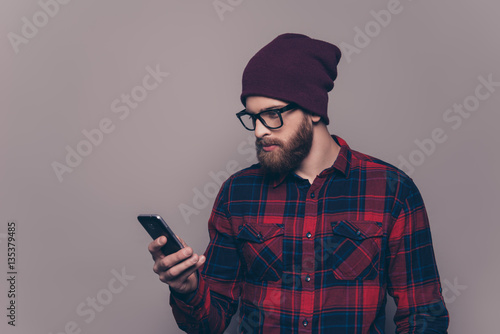 Concentrated bearded hipster man reading sms on smartphone © deagreez