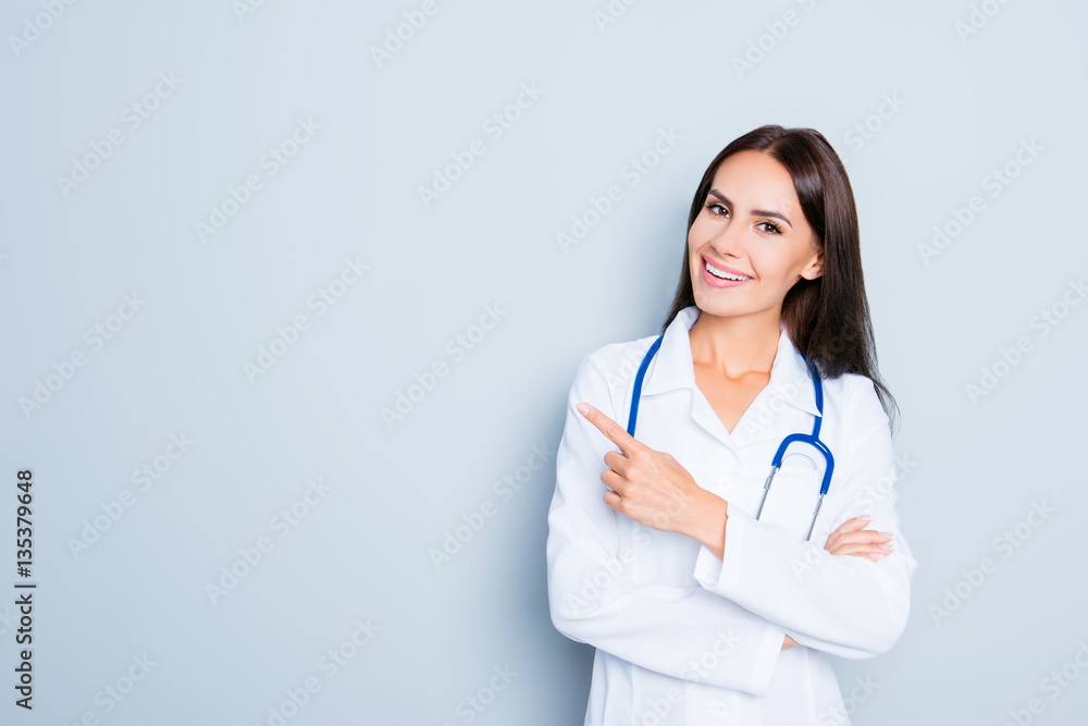 Friendly smiling young female doctor pointing with finger Friendly smiling young female doctor pointing with finger