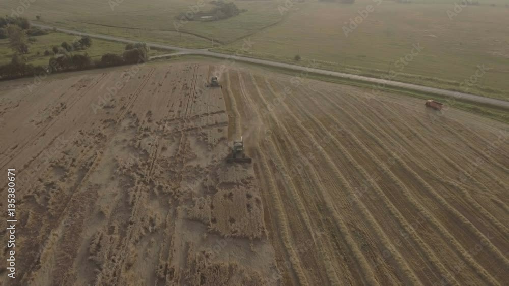 Two combine harvester on a wheat field at harvest.Aerial view of agricultural land with harvester.Combine harvesting wheat.Aerial view of agricultural land with harvester. Working Harvesting Combine Two combine harvester on a wheat field at harvest.Aerial view of agricultural land with harvester.Combine harvesting wheat.Aerial view of agricultural land with harvester. Working Harvesting Combine