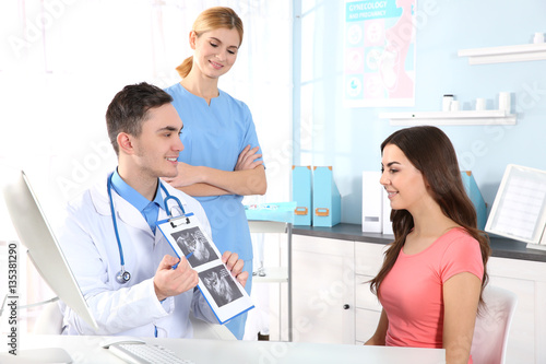 Doctor showing baby ultrasound image to pregnant woman