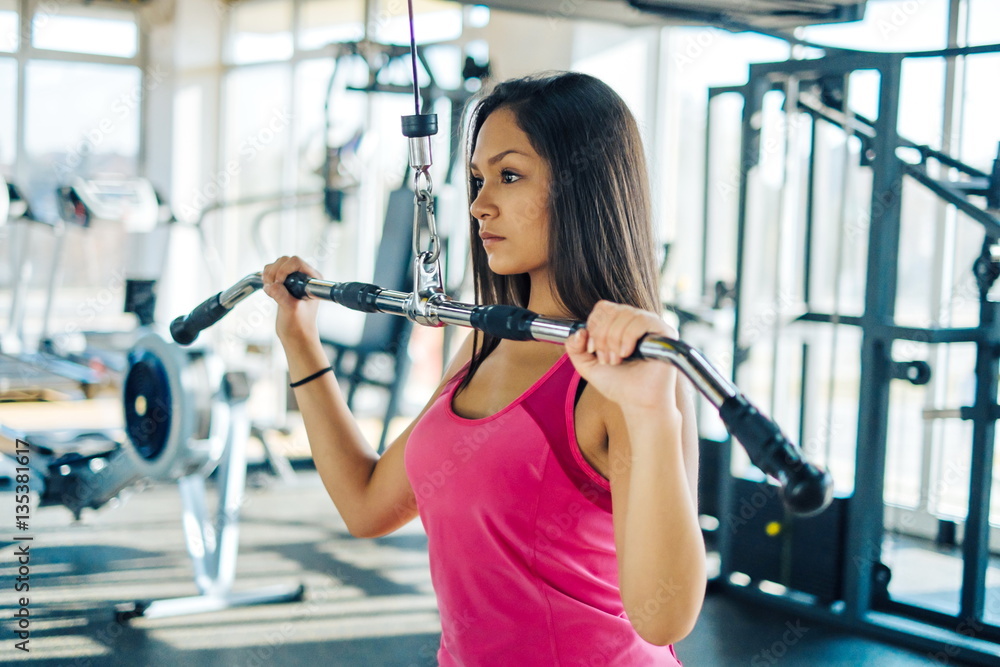 Beautiful young fitness girl in gym. doing lat machine exercises Beautiful young fitness girl in gym. doing lat machine exercises
