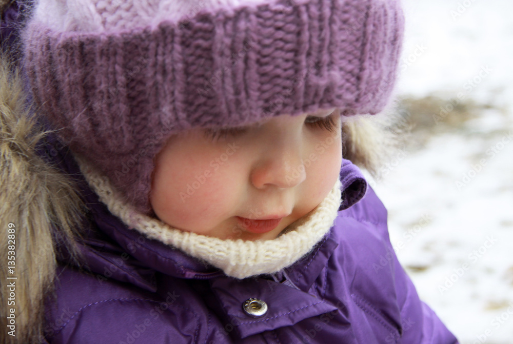 Child in lilac winter clothes looking down Child in lilac winter clothes looking down
