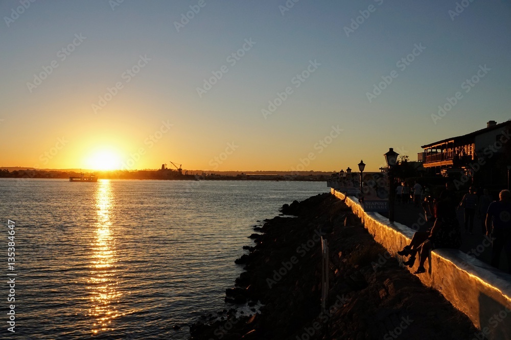 people sitting on ledge at sunset feet dangling in san diego looking at coronado people sitting on ledge at sunset feet dangling in san diego looking at coronado