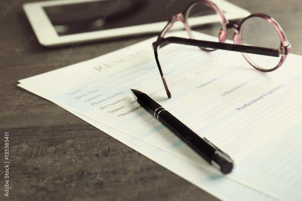 Resume, eyeglasses and pen on grey table, closeup Resume, eyeglasses and pen on grey table, closeup