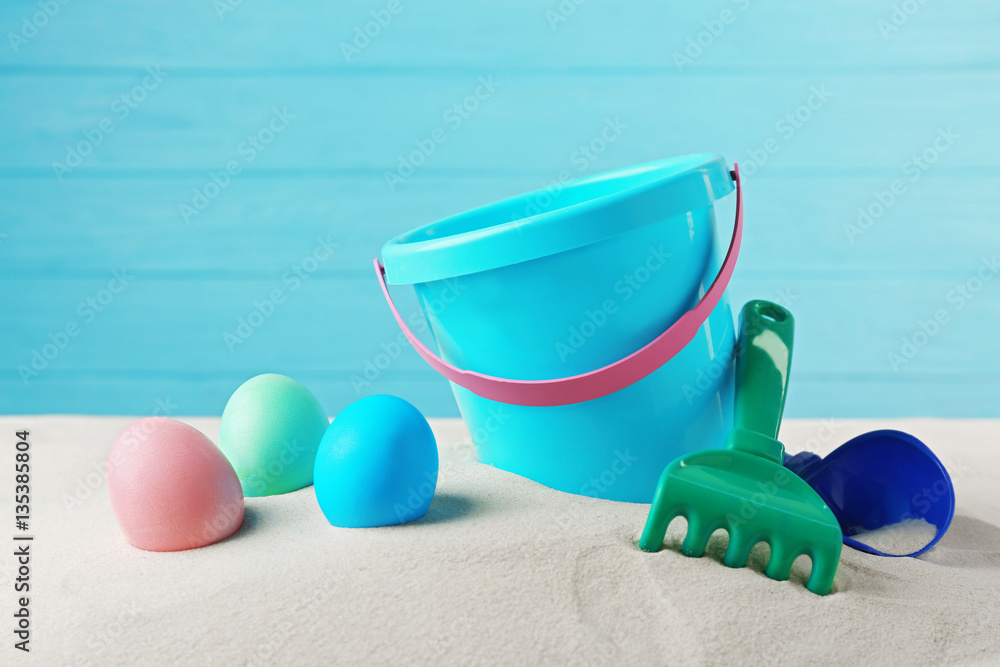 Easter eggs with sand and pail, on wooden blue background Easter eggs with sand and pail, on wooden blue background