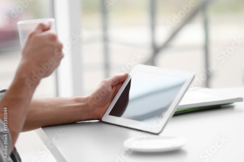 Handsome young man with tablet drinking coffee at home © Africa Studio