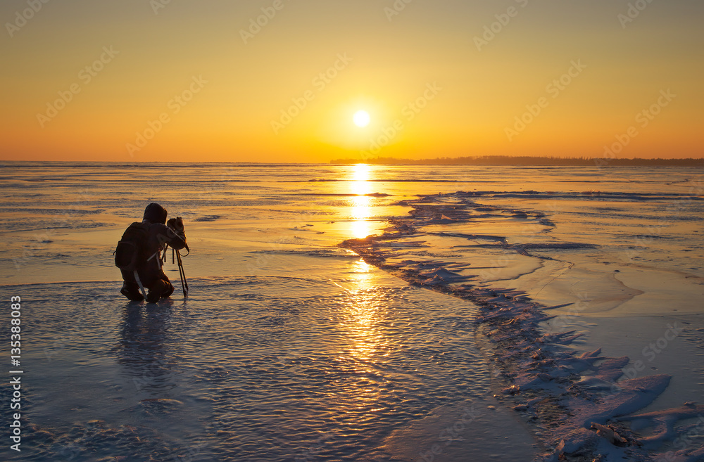 Obraz premium Photographer take pictures on the ice during sunset